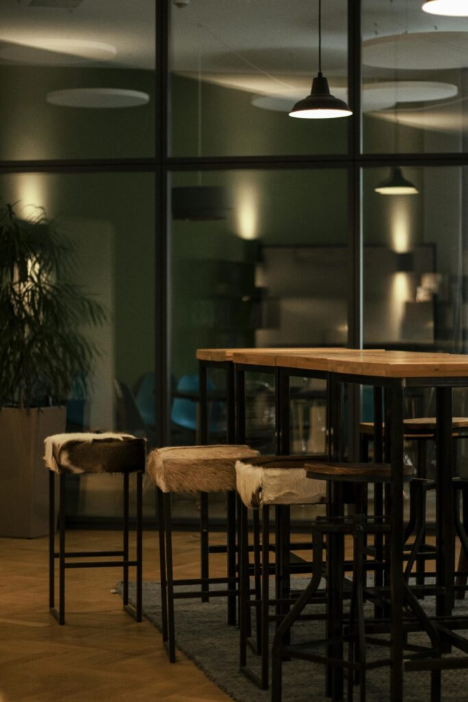 A modern office canteen featuring high tables, stools, and ambient lighting in a contemporary setting.